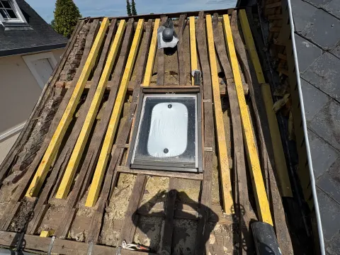 Charpente rénovée et ardoise reposée autour d'un velux par un couvreur à Rouen